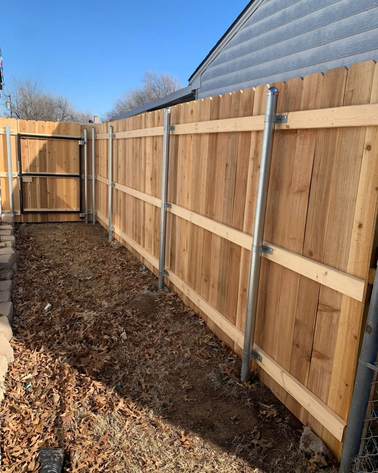 Newly installed cedar privacy fence on galvanized steel posts along a side yard