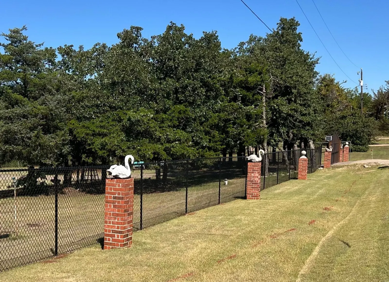 Black chain-link fence with decorative red-brick columns along a property line