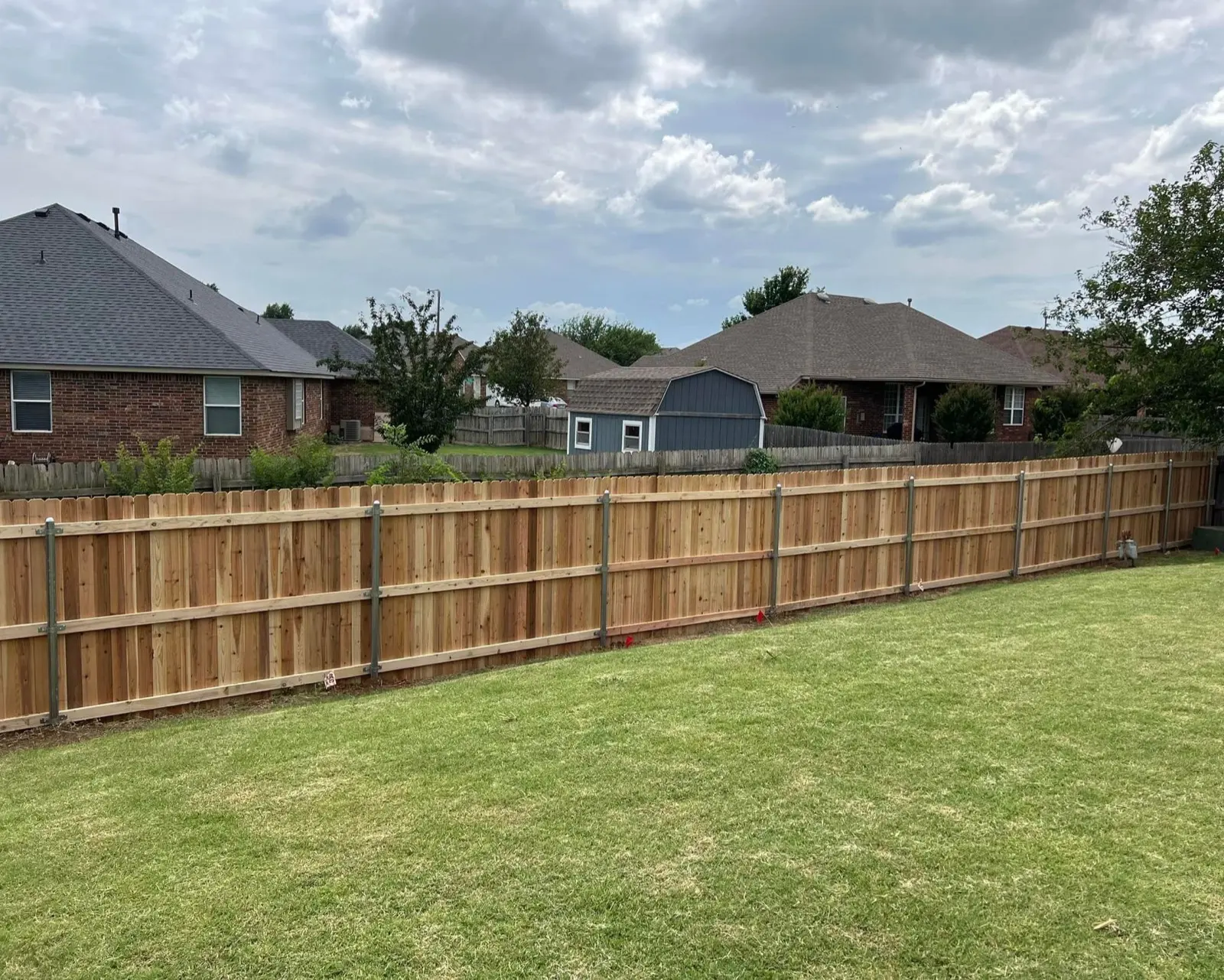 Cedar privacy fence enclosing a full backyard with houses behind