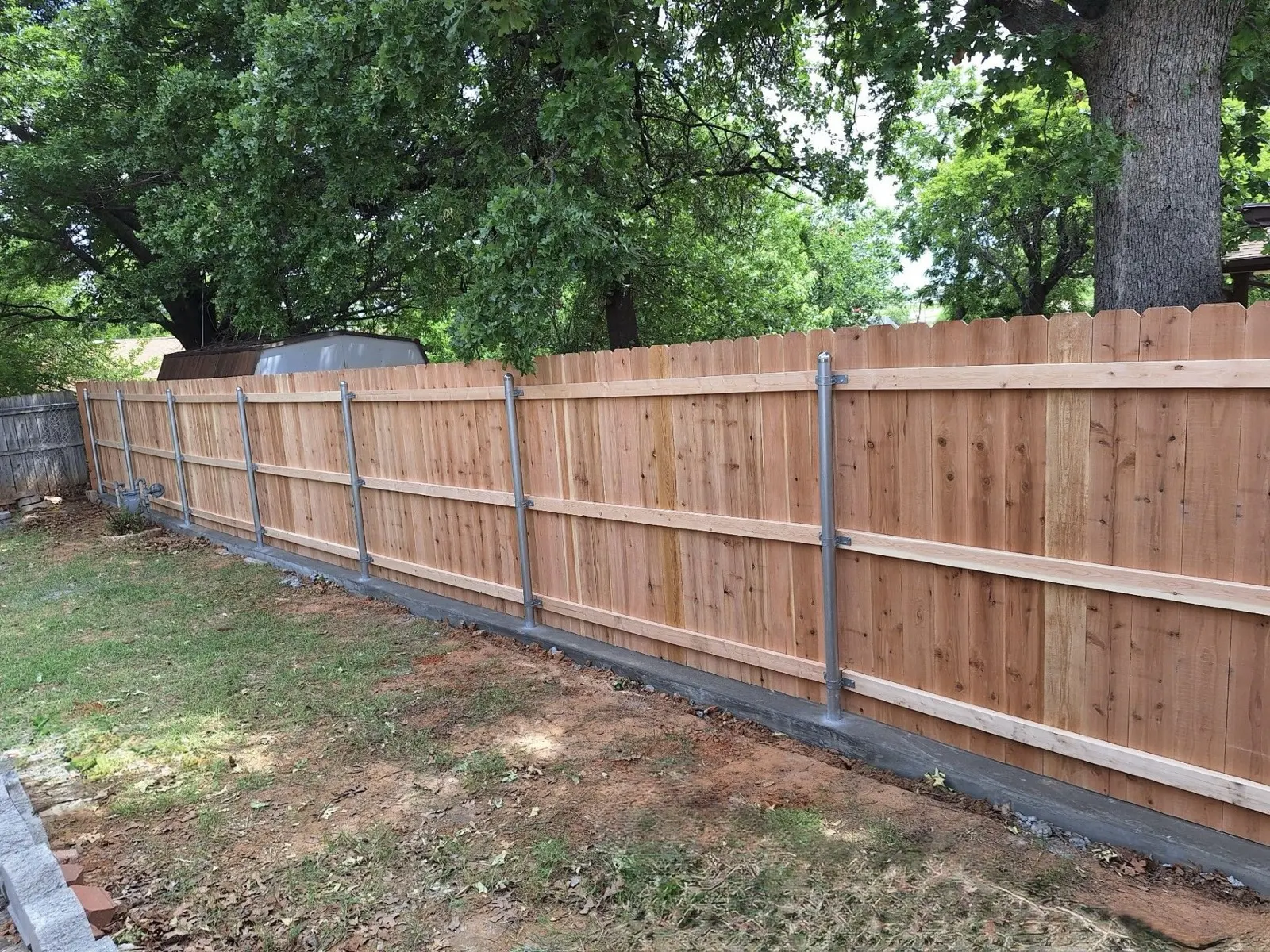 Wood privacy fence built on steel frame posts across a backyard